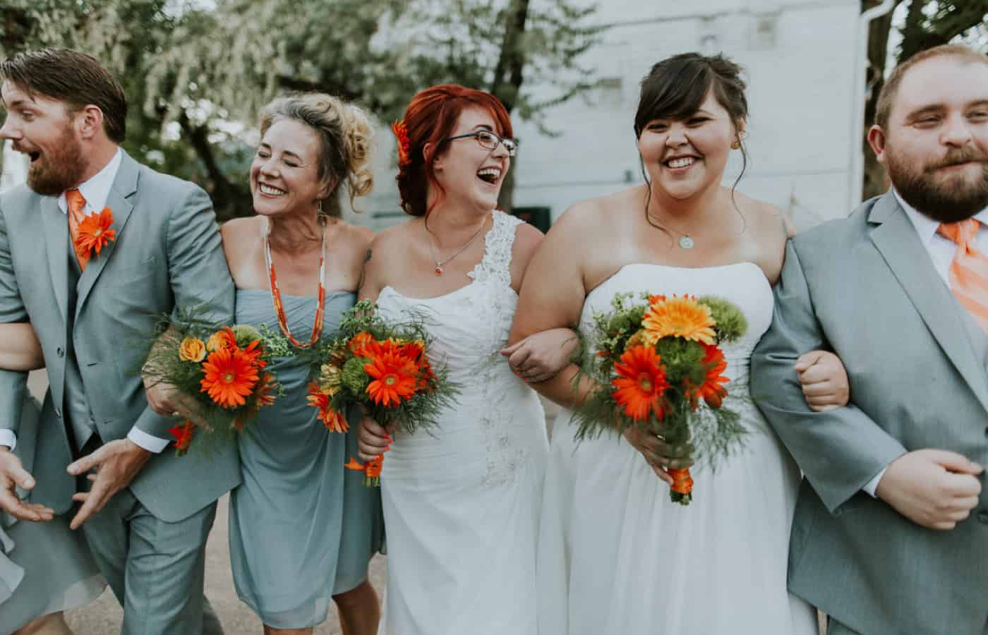 A bride laughs while walking arm-in-arm with her wedding party