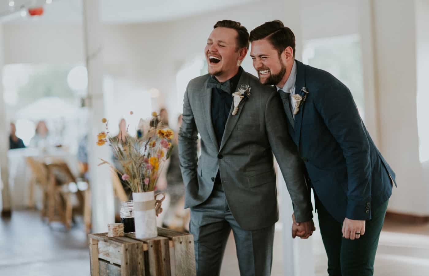 Two brooms laugh during the toasts at their wedding