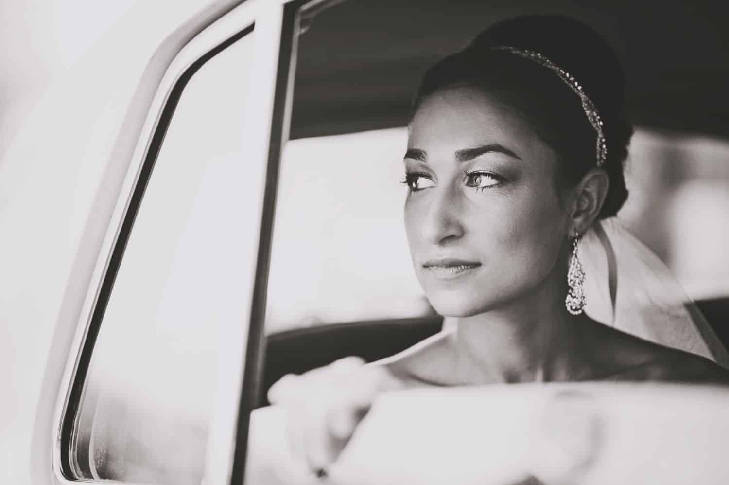 Photo of bride through car window with tear on her cheek. By Harris & Co.