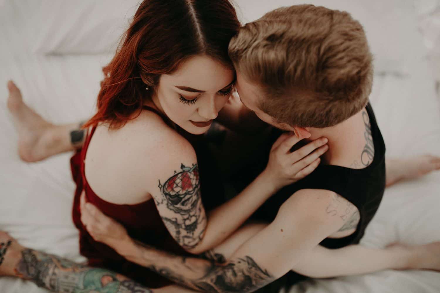 This Is the Boudoir Photography Shy Couples Need To See: Tattooed Couple Sits Close On Bed