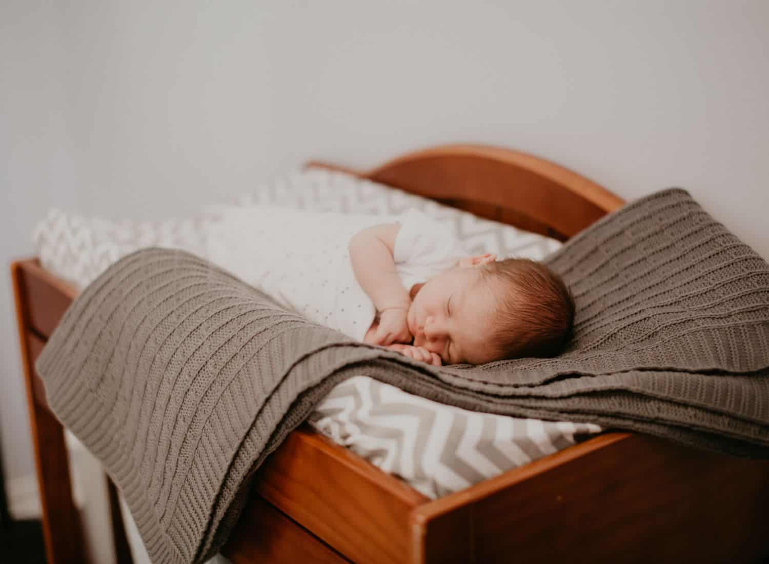 Lifestyle Newborn Photos: In this nap-time photo, a newborn baby lies on a knitted blanket bathed in windowlight.