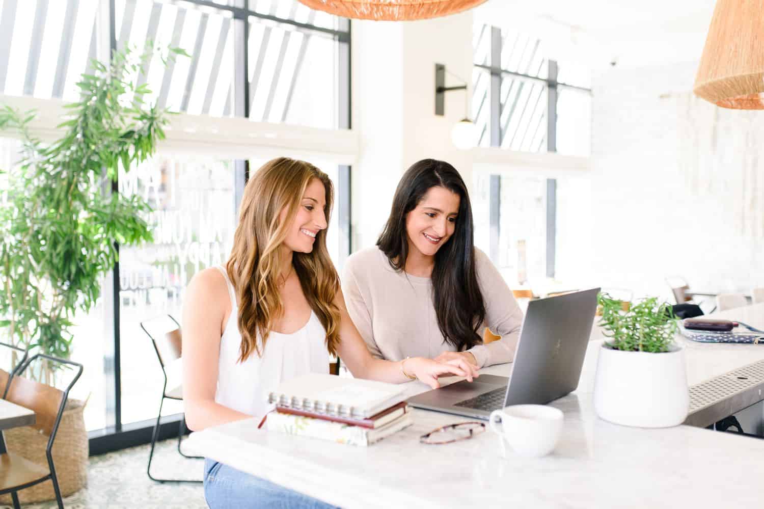 Women working at a laptop in a bright office.