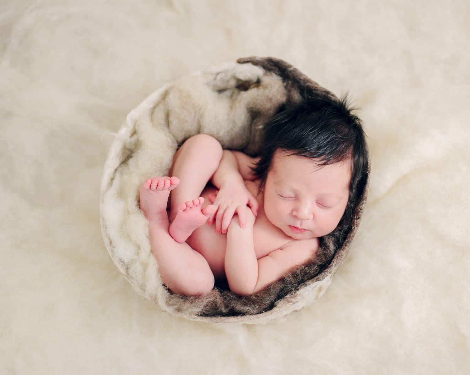 Hate in-person sales? Here’s how to sell albums online! | A newborn client is posed in a small basket, surrounded by fleece blankets.
