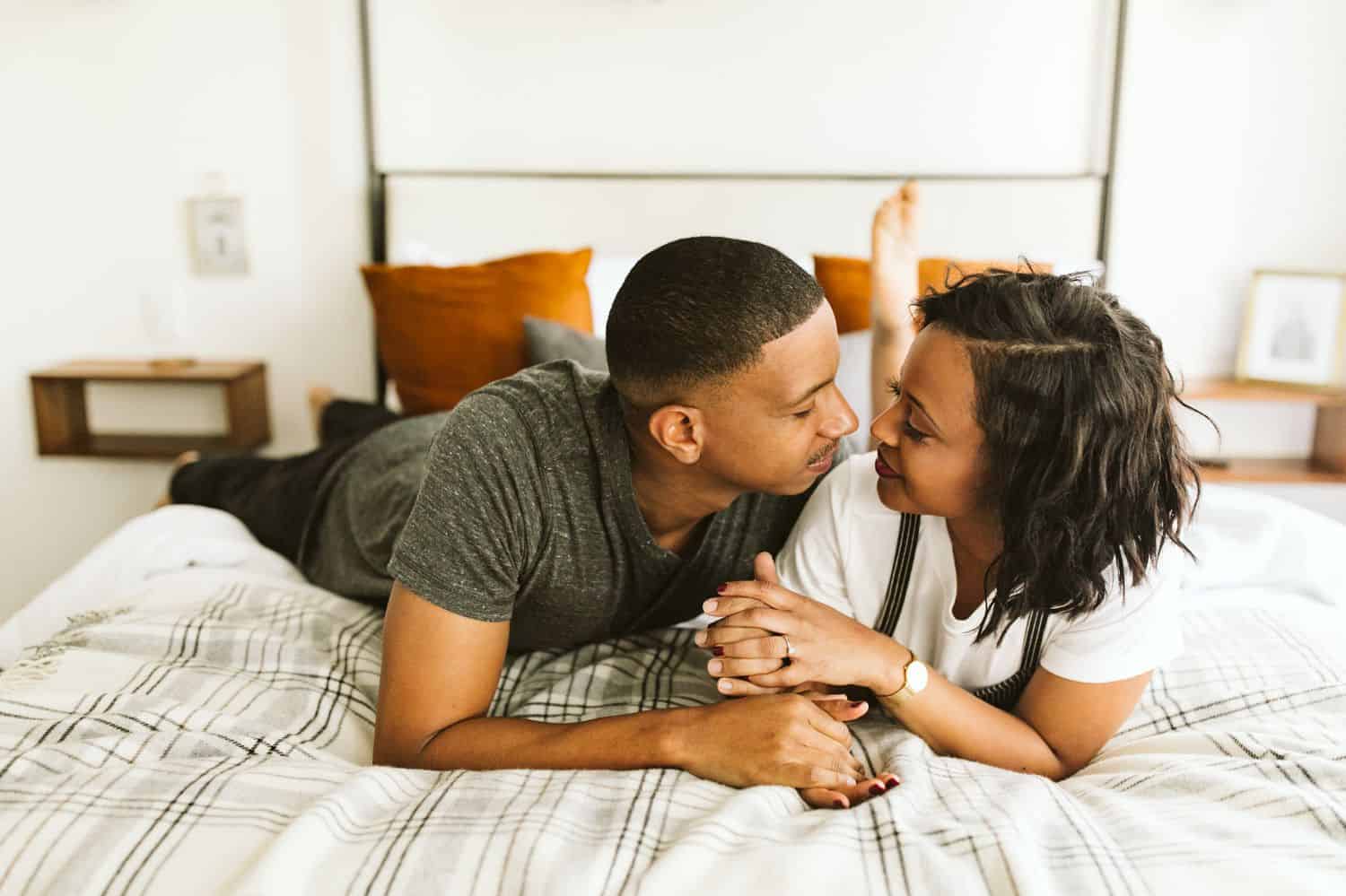 A Black couple cuddles in the master bedroom of their beautifully lit Atlanta Airbnb