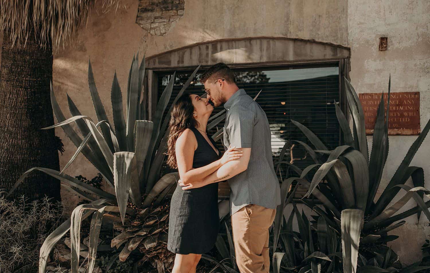 A couple kisses in the shady courtyard of a Texas building