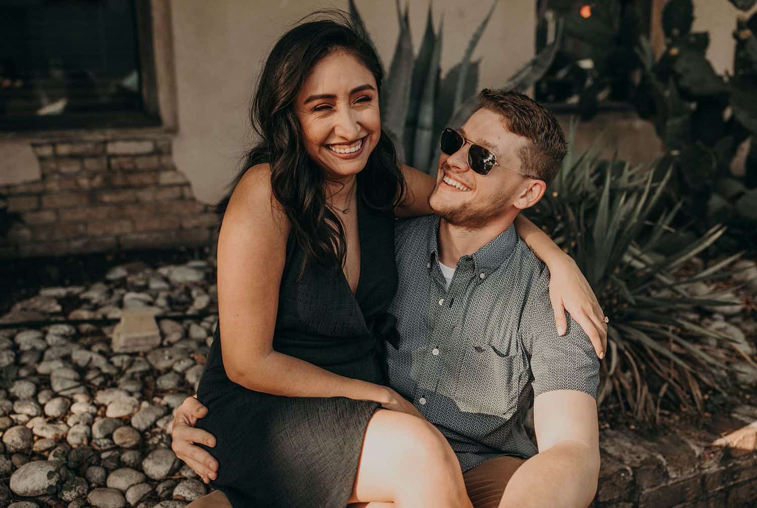 A woman sits in her husband's lap for their engagement session