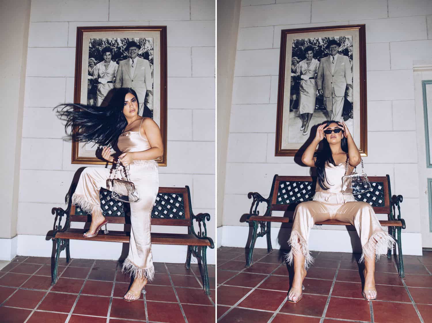 A black-haired model wearing all white poses on a wrought iron bench in front of an enormous framed photograph while tossing her hair
