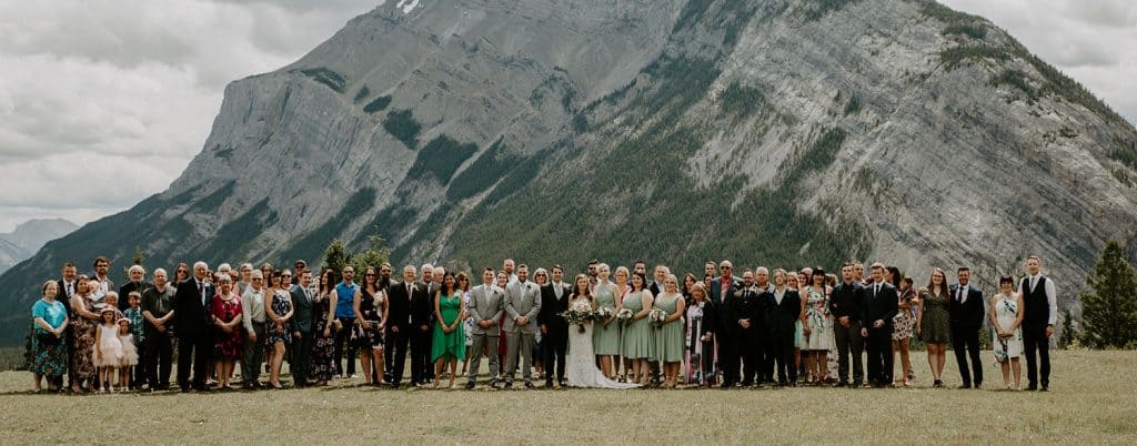 Large family portrait at a wedding in front of a mountain