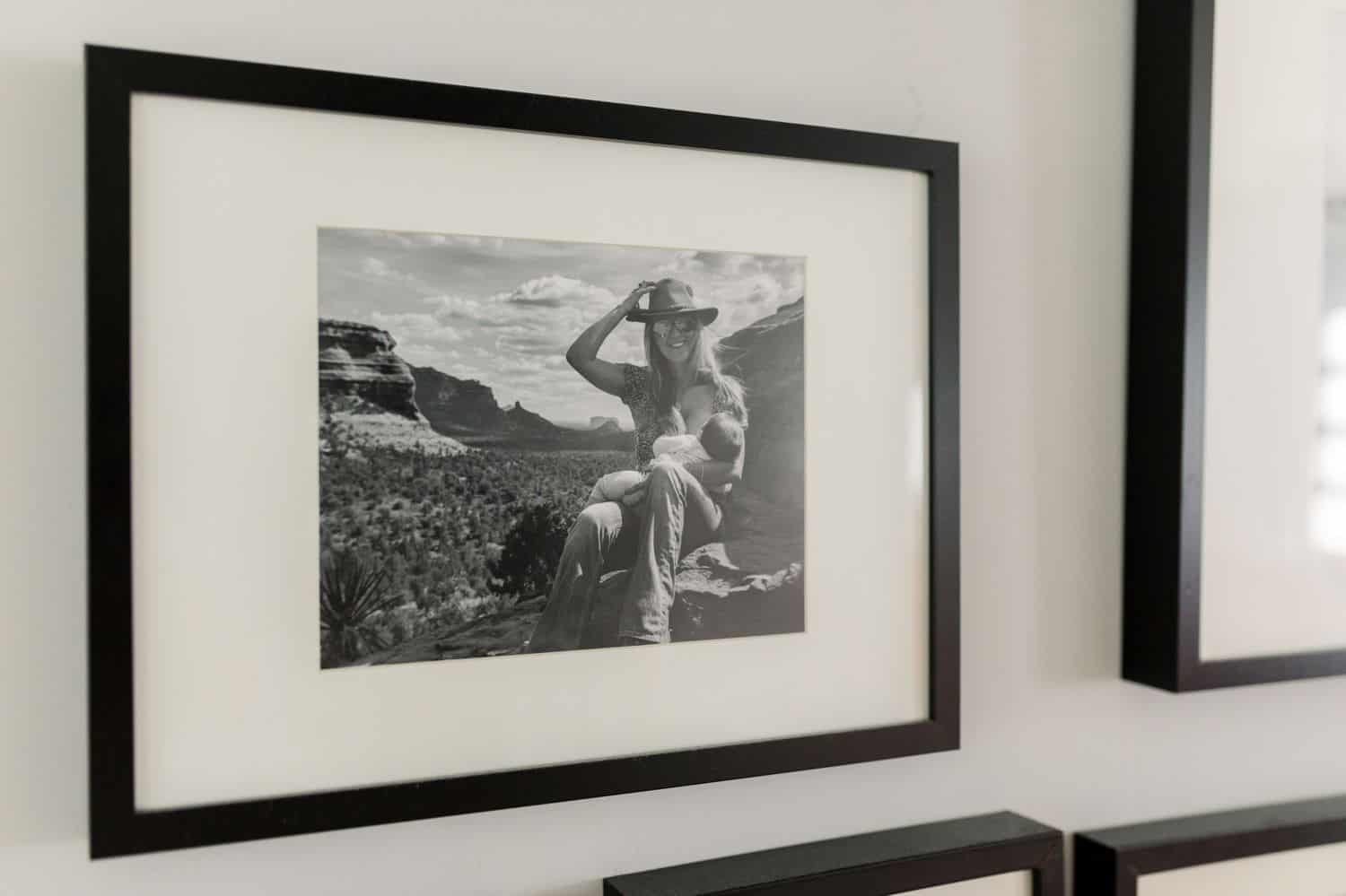 A black and white portrait of a woman in a cowboy hat is framed and hanging on a white wall