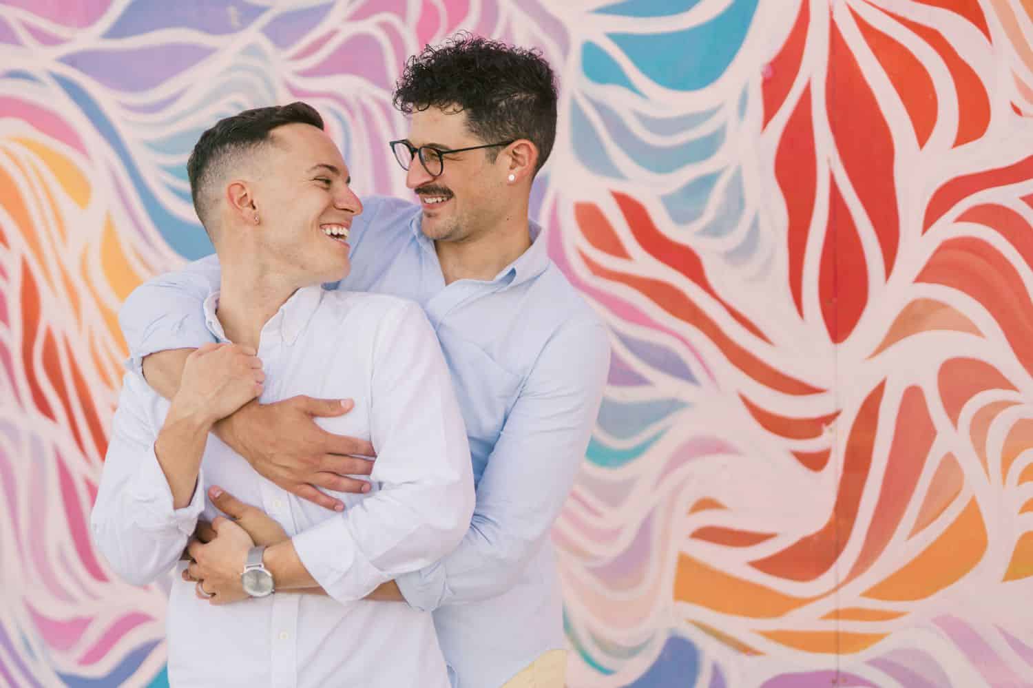 A couple posing against a colorful backdrop