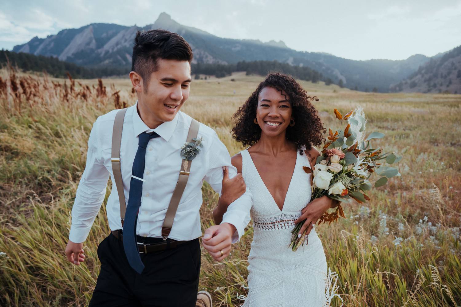 Customer Loyalty: By Nick Sparks, a bride and groom stroll together through a field of wheat with the Denver Mountains in the background.