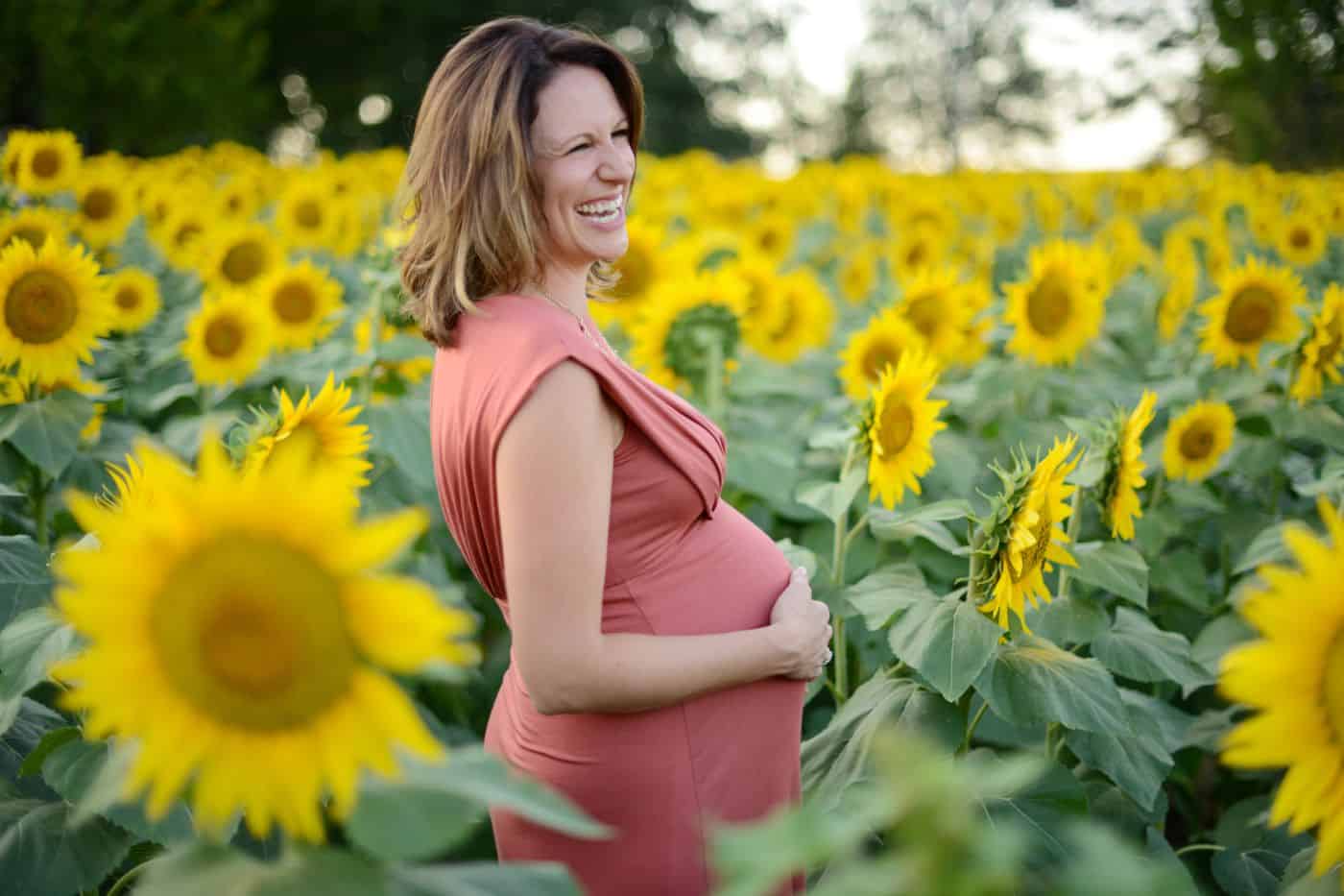 Andrea Nigh's simple maternity poses include this casual portrait of a mom-to-be holding her belly in a sunflower field
