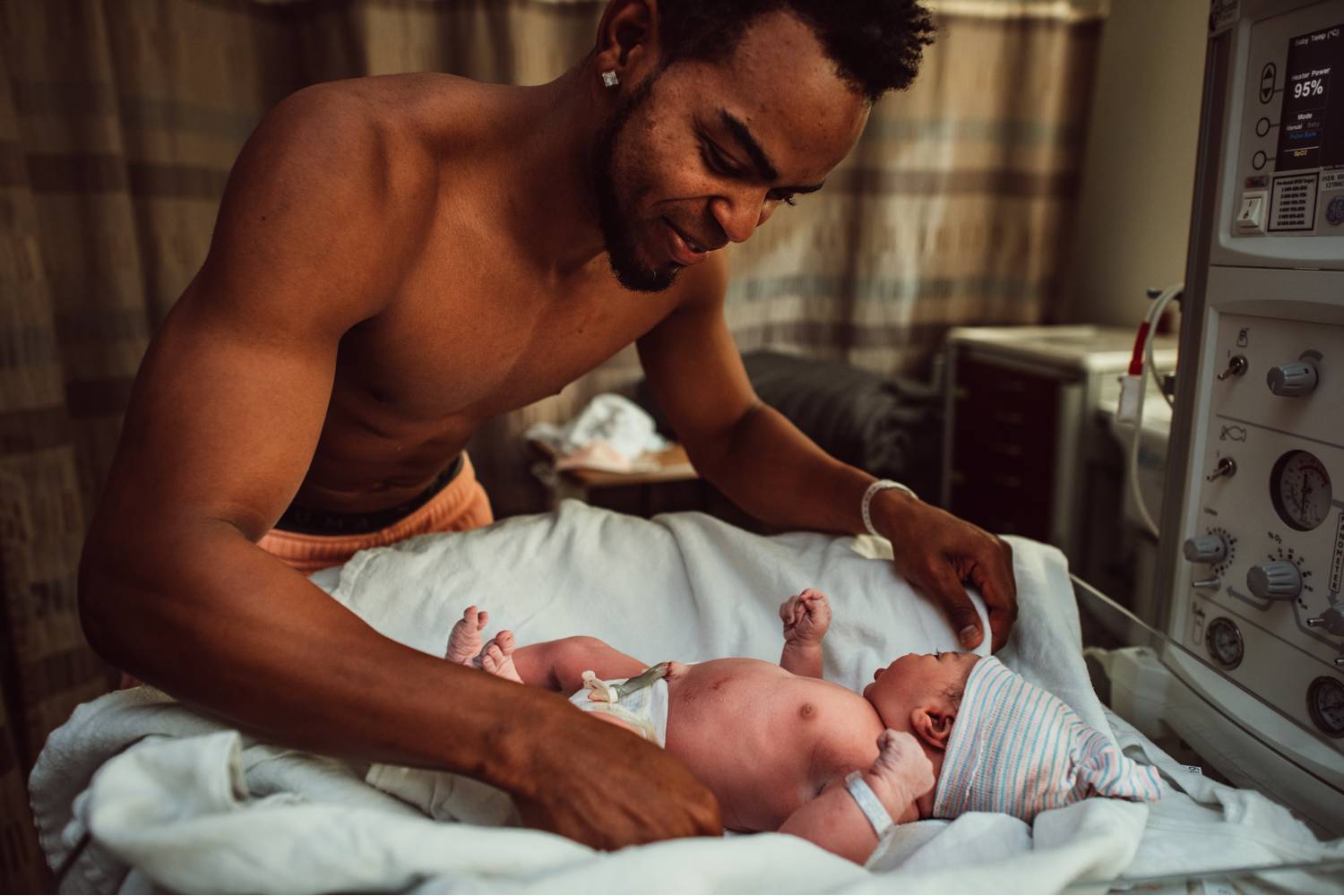 A new father swaddles his newborn baby