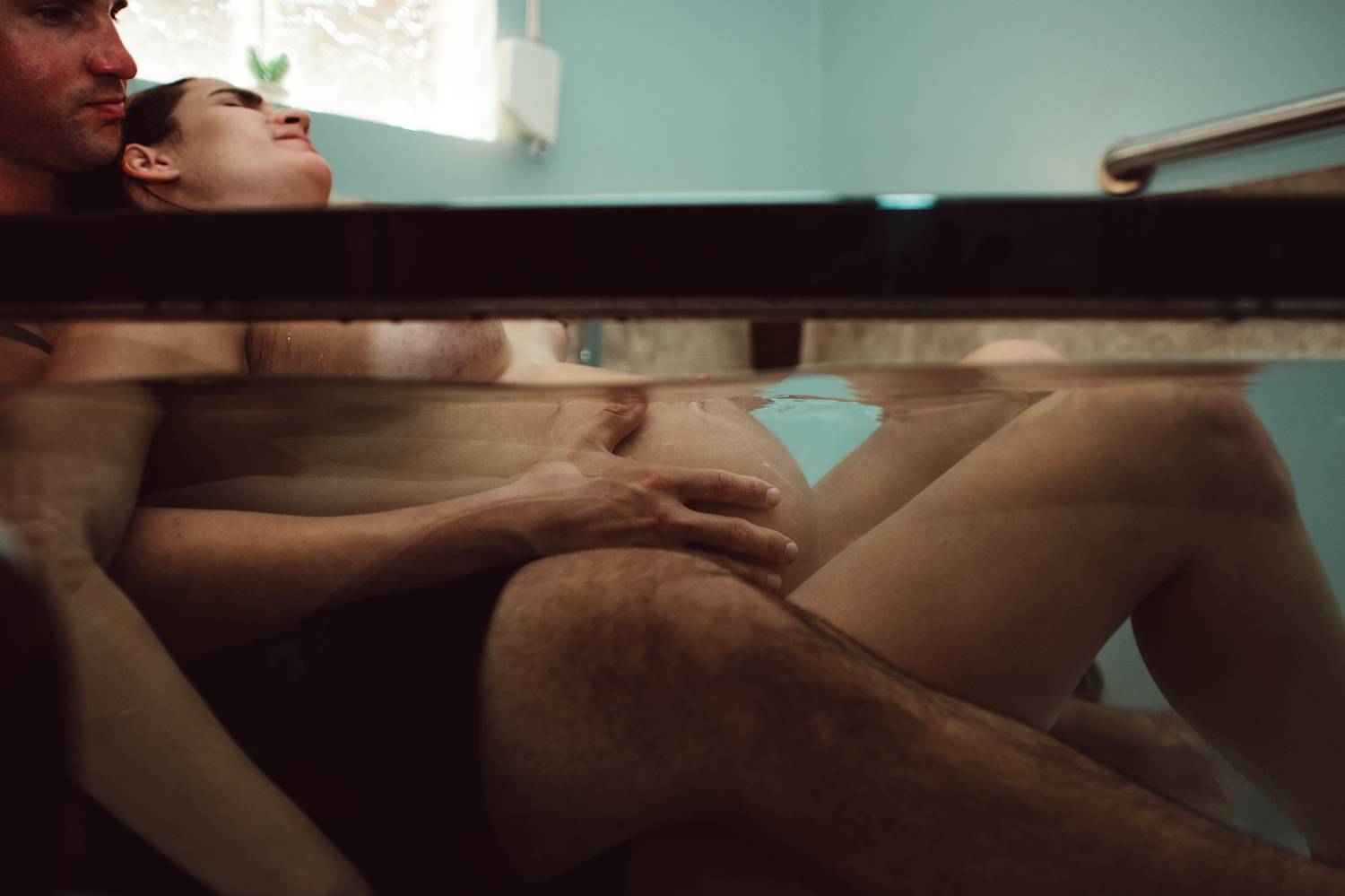 A couple reclines in an inflatable bath at home as the pregnant partner labors