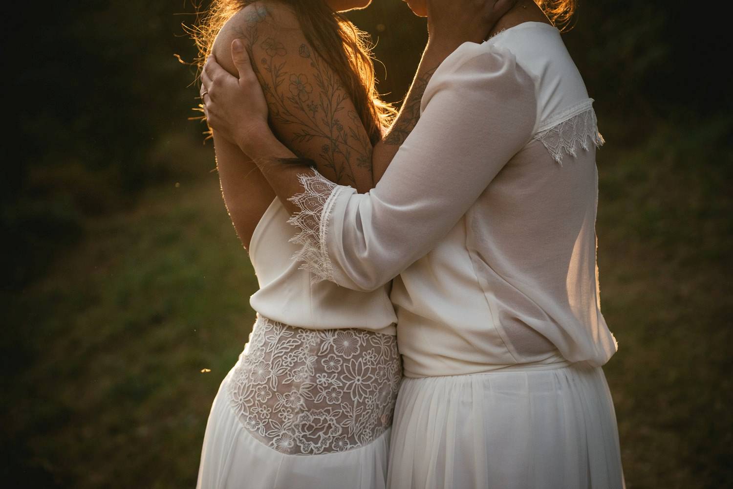 This detail shot of two women embracing belly-to-belly shows off the gorgeous details of their wedding dresses