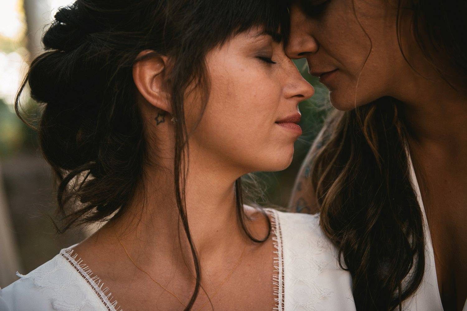 Two brides lean toward each other until their foreheads are touching