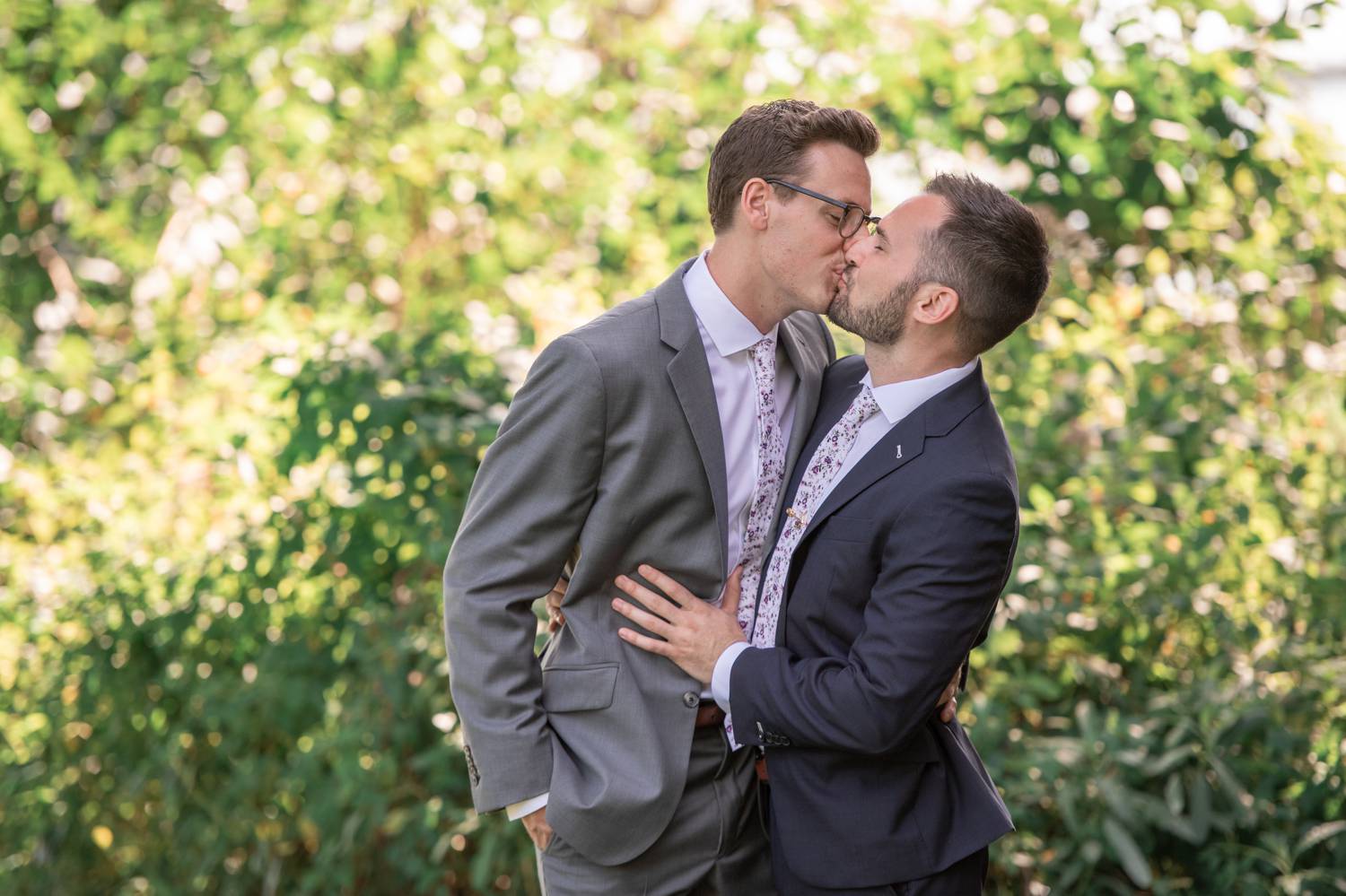 Two grooms kiss outside on their wedding day
