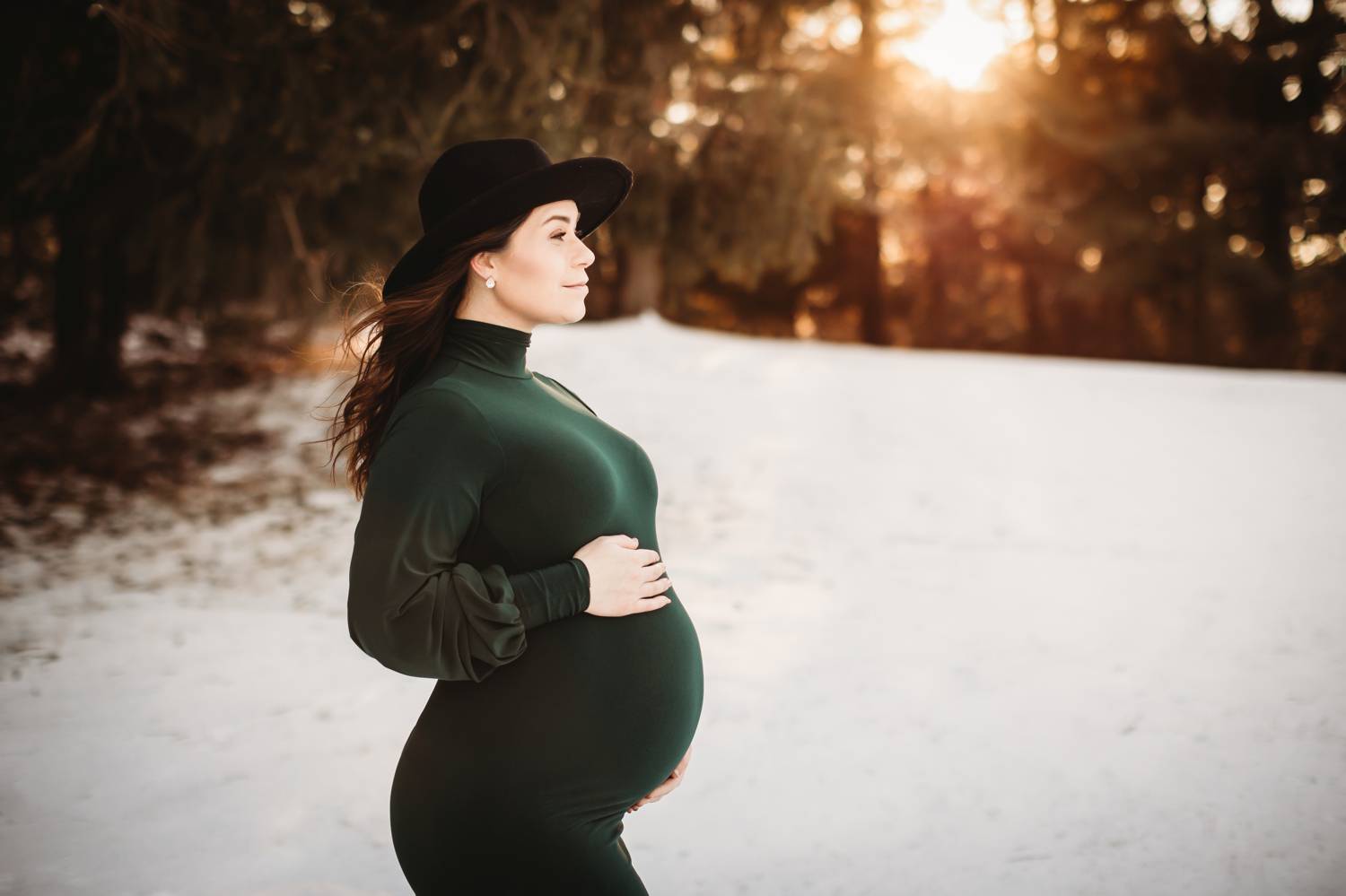 winter maternity portrait in the snow with a green dress