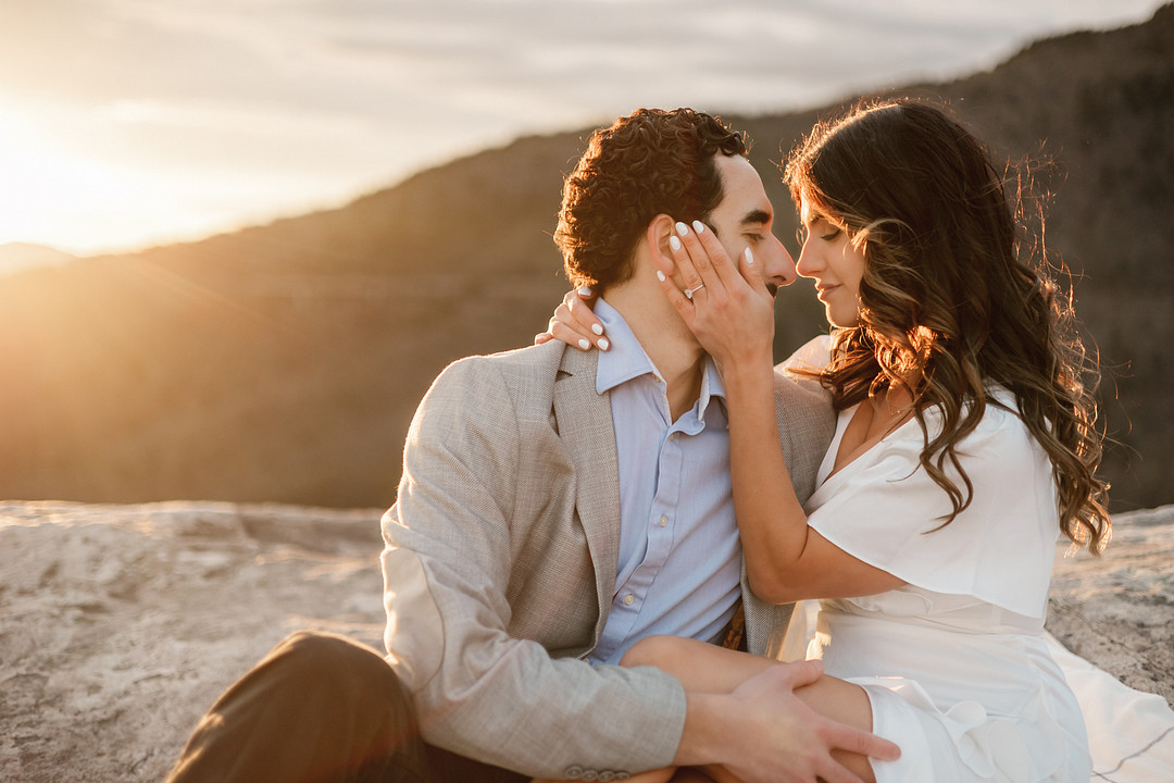 Wedding photograph of couple sitting on a rock at sunset