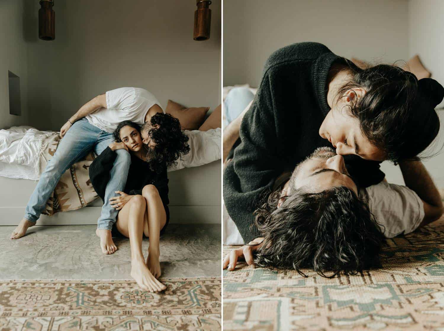 A dark-haired couple in casual clothing kisses on the floor and cuddles close on their bed for a low-key boudoir session in a minimalist space.