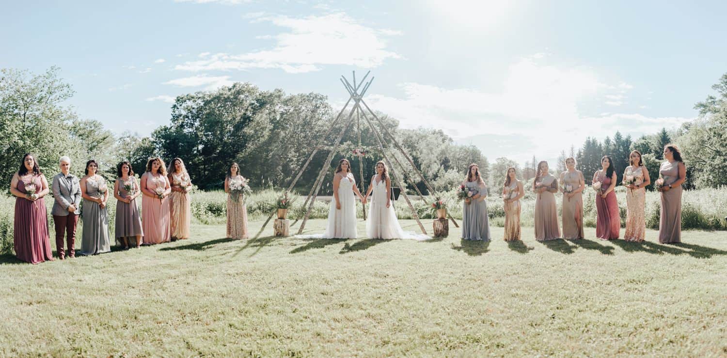 A wedding couple together with bridesmaids on a grassy field