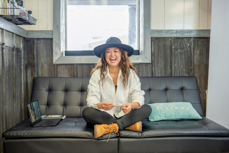 woman laughing on a grey couch
