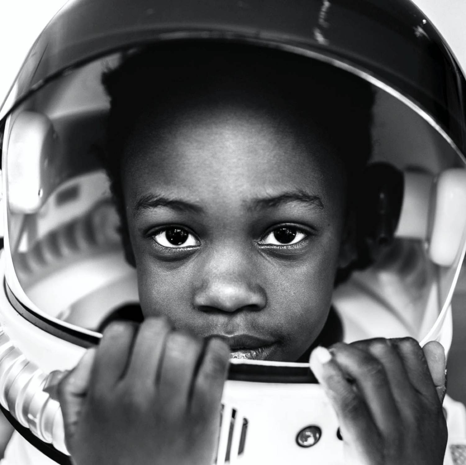 Adina Davis' black and white photo of a young Black child wearing an astronaut helmet.