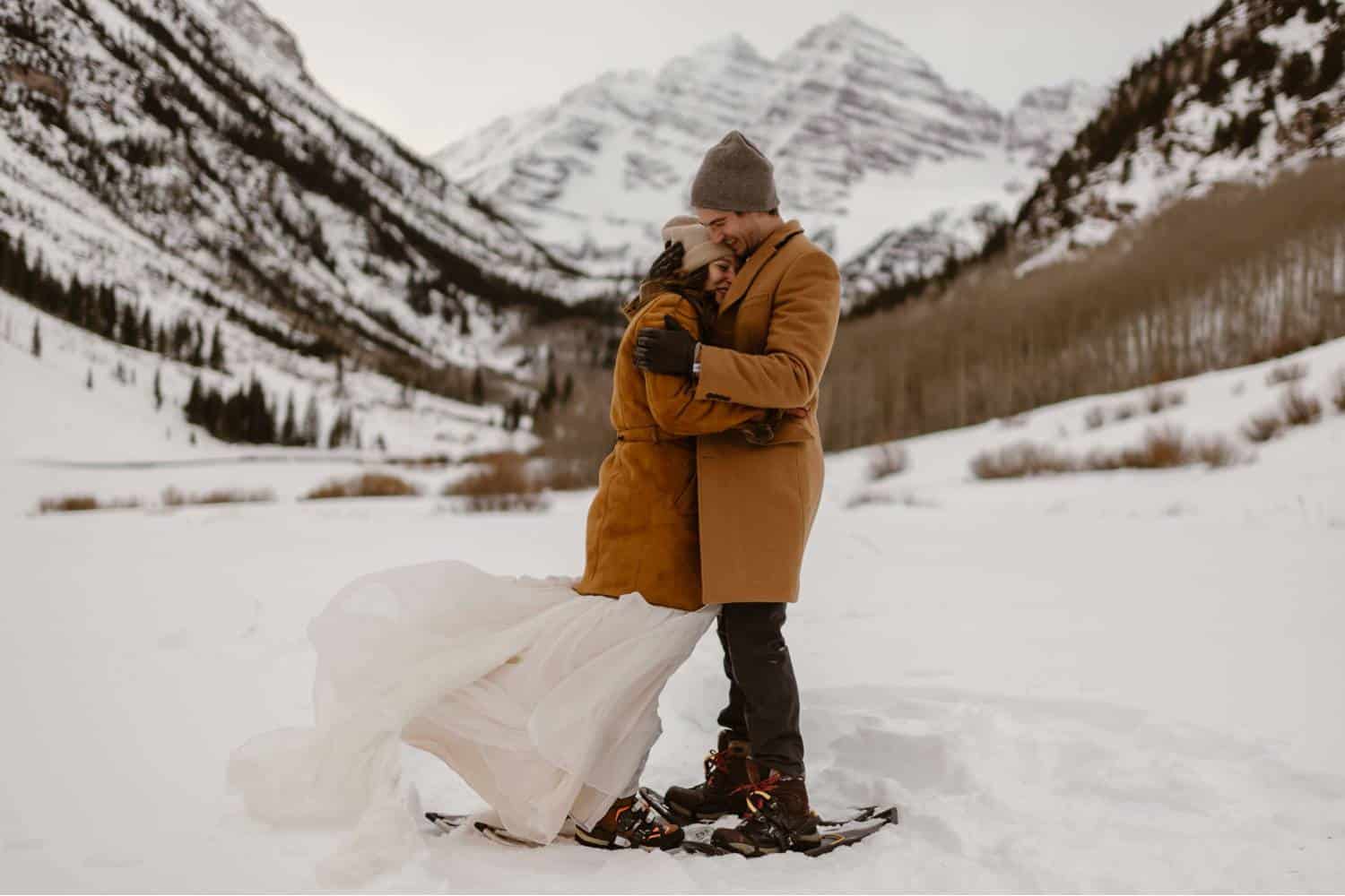 Adventure Instead's photo of newlyweds hugging in the snow. They're both wearing snow shoes.