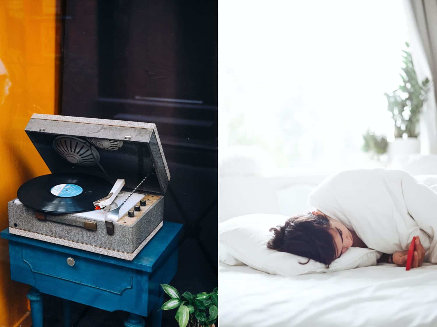 An open record player sits on a blue table by a yellow wall. A woman lies in a white bed looking at her smartphone.