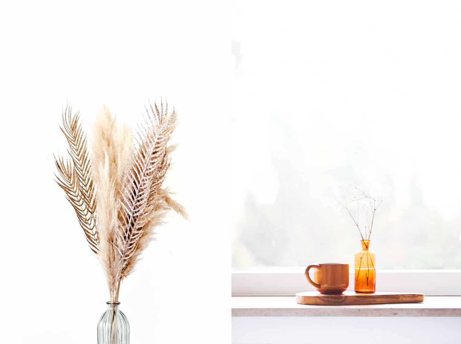 A vase of feathers sits in front of a window. A tray holding a mug and a diffuser sits in front of a window.