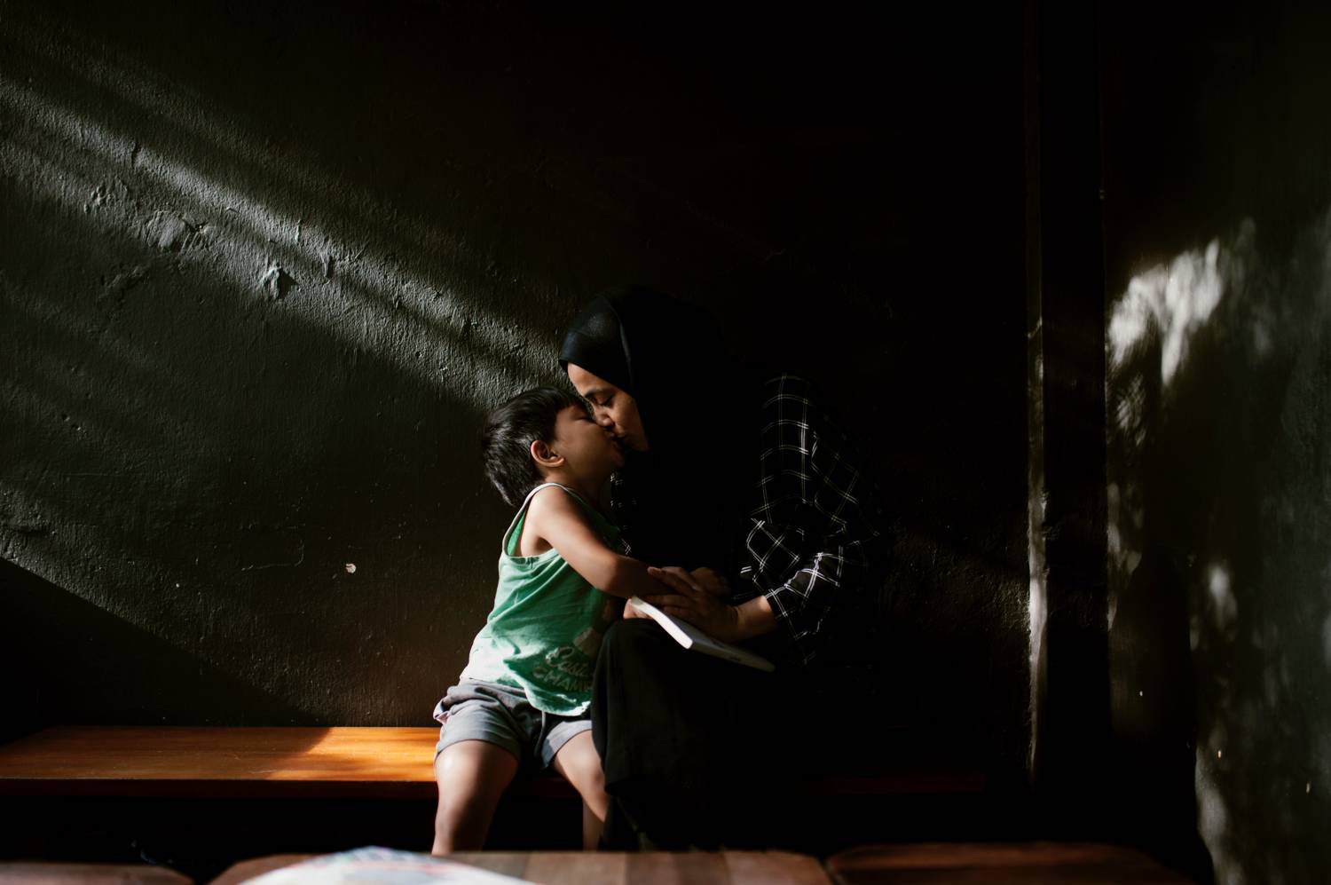Photo: Min Mohd's moody portrait shows a little boy kissing his mother as they lean into a beam of light.