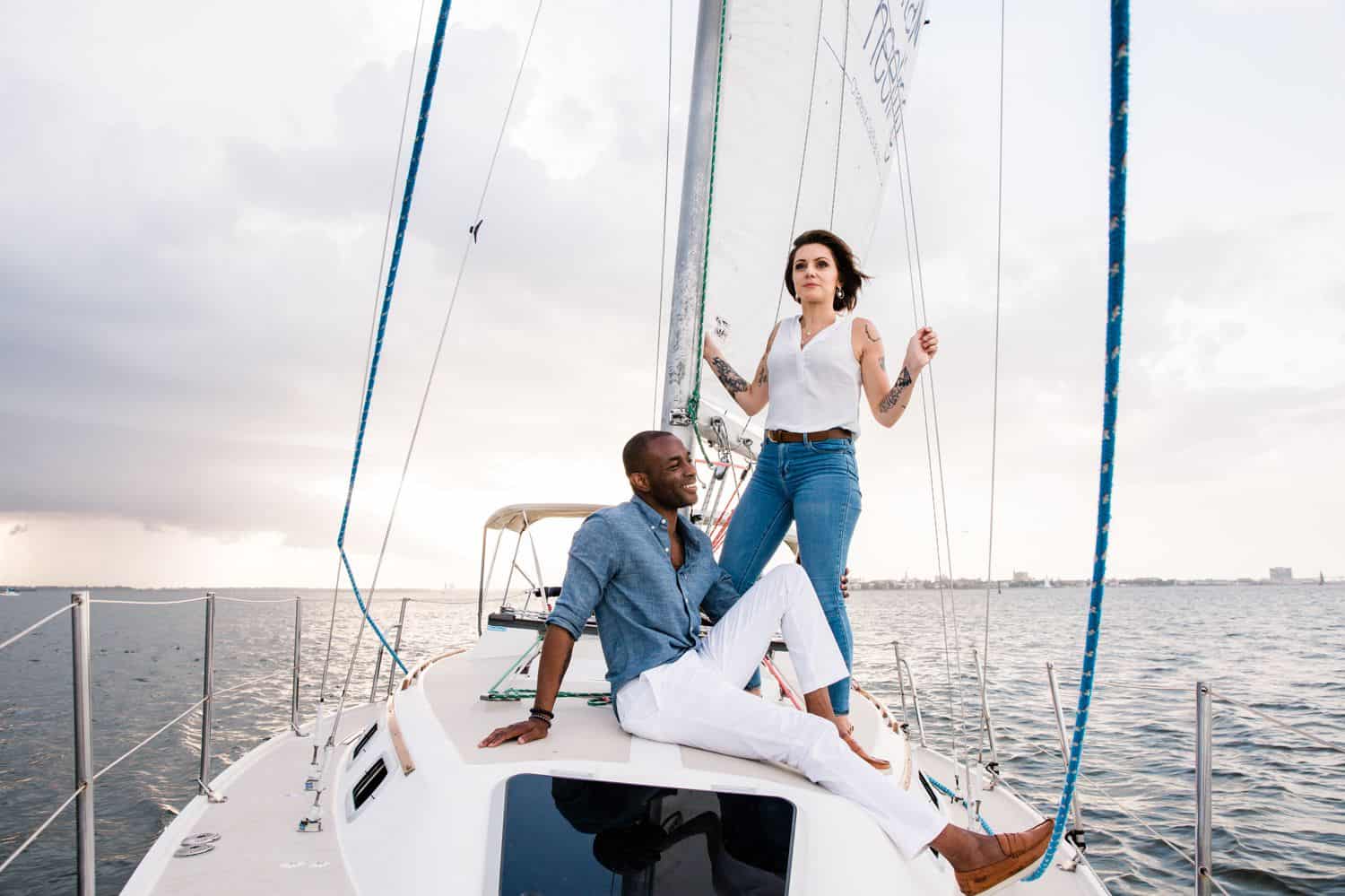 A Black man and a White woman sail on a sailboat